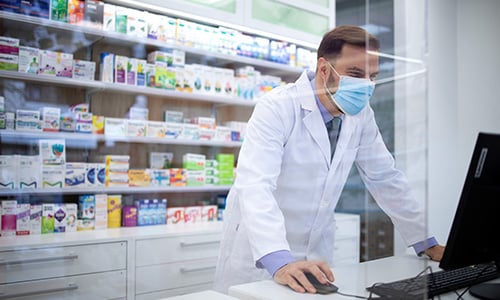 Pharmacist using healthcare IT solutions on computer screen for optimized patient care and efficient pharmacy management.